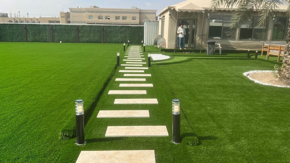 حديقة منزلية بالرياض بمسطح أخضر وممر حجري وإنارة أرضية وجلسة خارجية